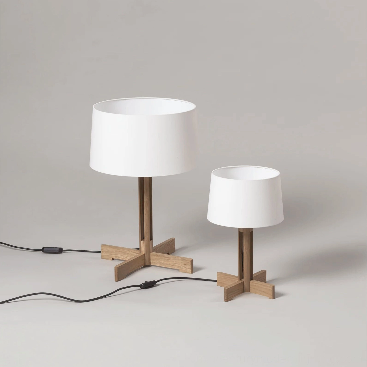 Two matching wooden table lamps different sizes side by side, minimalist neutral backdrop