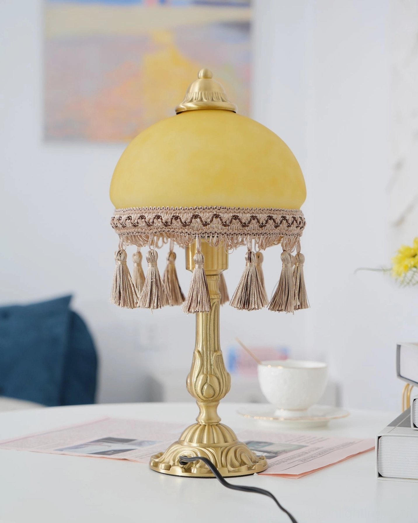 Brass table lamp with woven fabric tassels and brass metalwork in home lighting setting