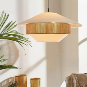 Woven pendant light hanging in indoor corner with tropical plants and bohemian décor, showing rattan detail