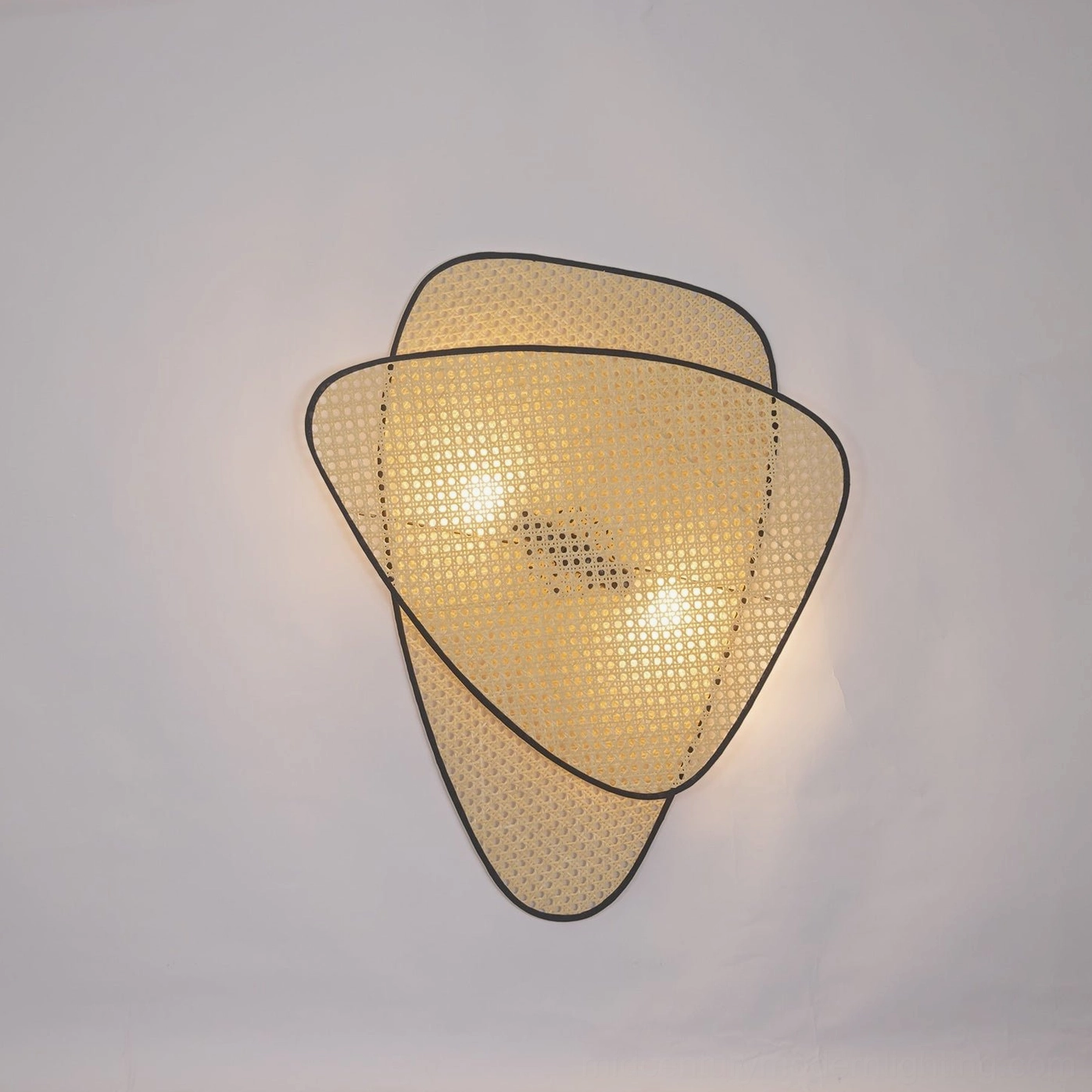 Rattan woven wall lamp displaying warm light diffusion through bamboo cannage pattern creating shadow effect