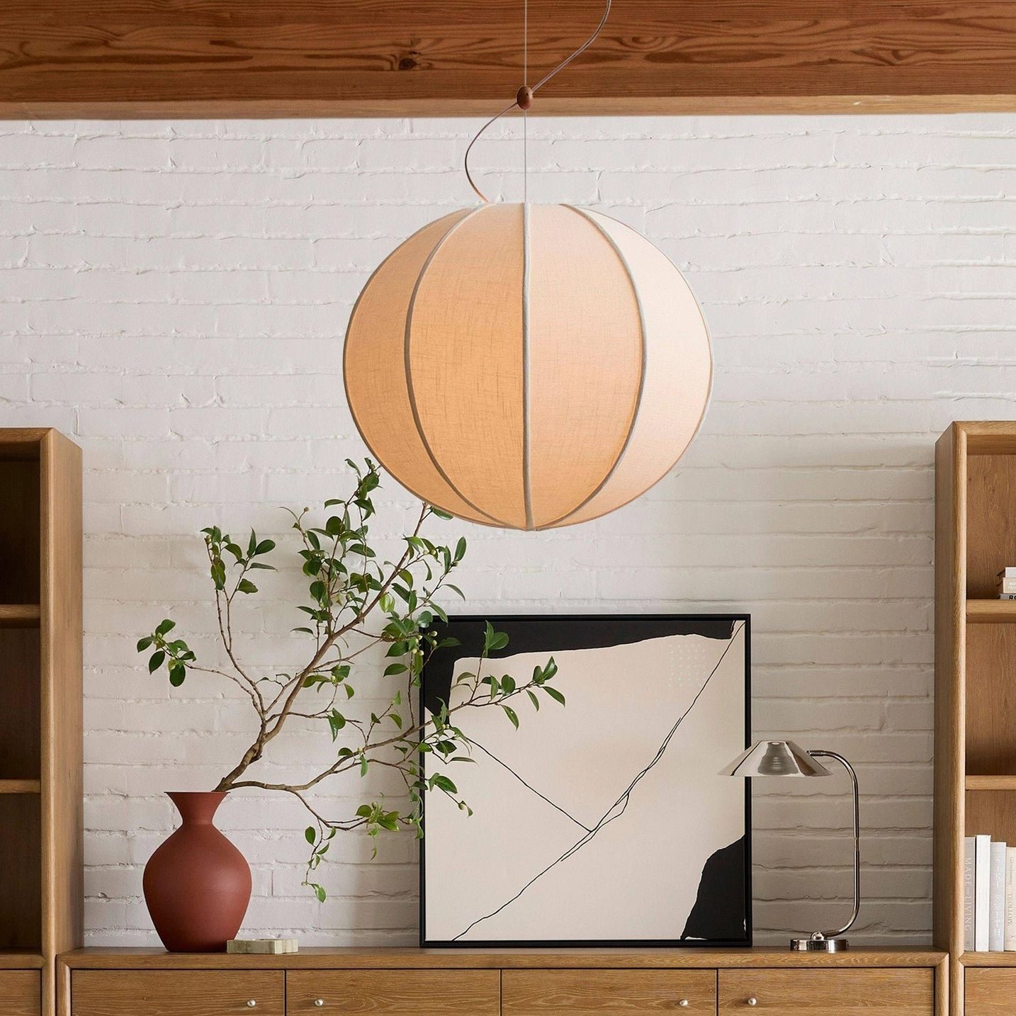 Warm beige Yaratam spherical pendant with linen texture visible from side angle in minimalist space