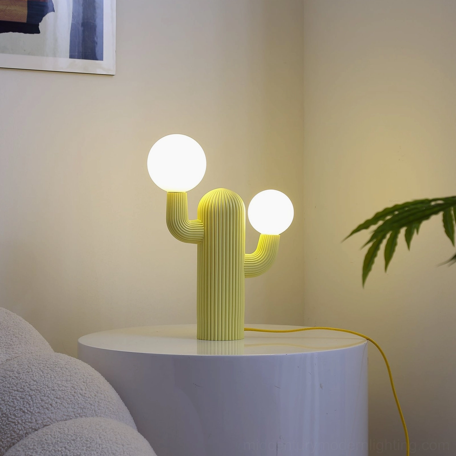 Yellow sculptural cactus table lamp with illuminated warm globe bulbs in cozy living room with plush sofa