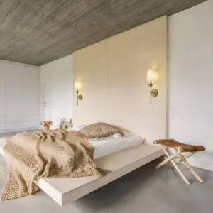Pair of matching antique brass wall sconces in modern bedroom with warm ambient lighting