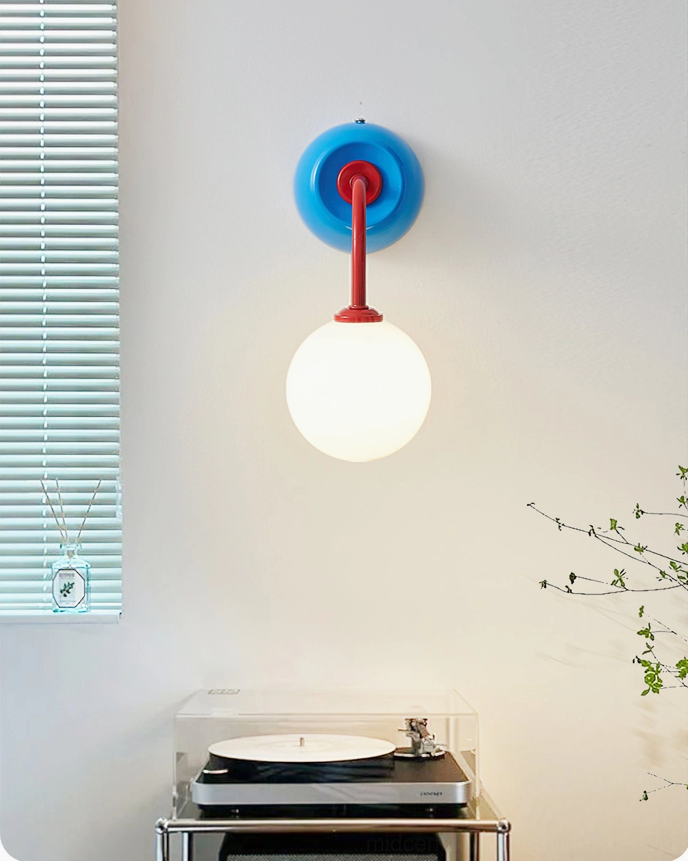 Blue-base Zesta modern wall sconce with compact sleek design, mounted above minimalist wall featuring vinyl turntable and records setup