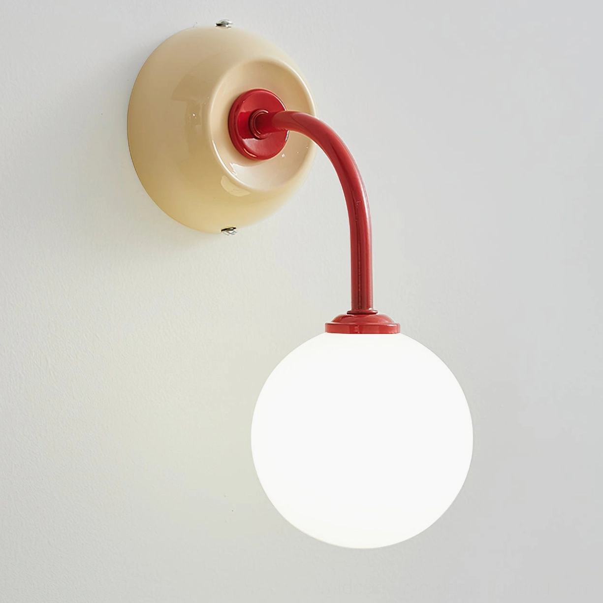 Mid-century modern inspired Zesta wall sconce with frosted glass globe and sculptural metal frame, mounted in styled interior setting