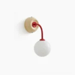 Zesta modern wall sconce with beige-red frosted white color scheme, featuring spherical glass diffuser and metal arm, frontal view on minimalist white wall