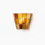 Zola leaded glass wall sconce with amber stained glass and metal frame, frontal close-up view against white studio background